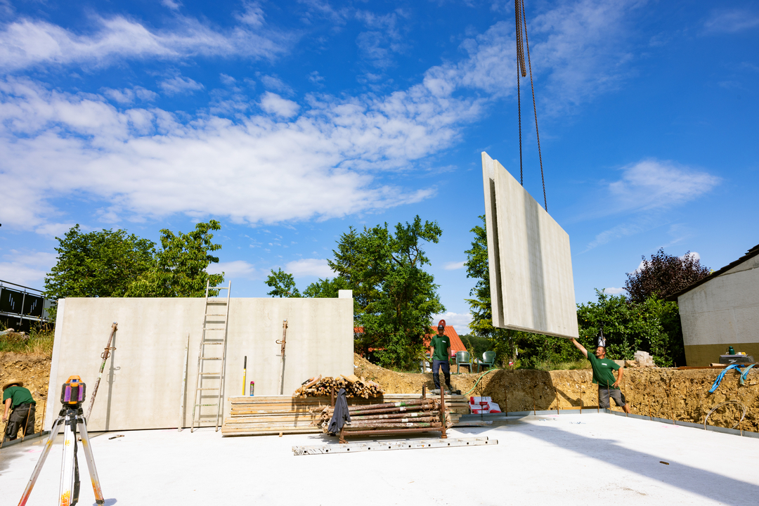 Fertigelementwand wird per Kran auf Fundament gesetzt