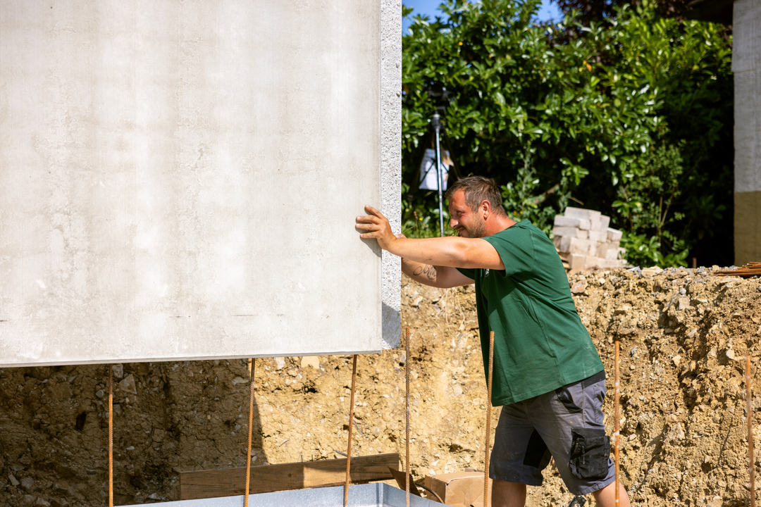 Bauarbeiter richtet Betonwand auf Baustelle aus