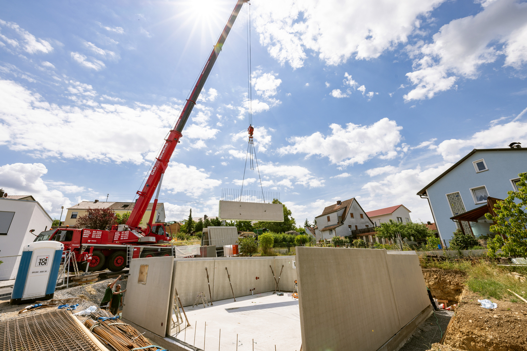 Kran hebt Betonelement in Baugrube ein