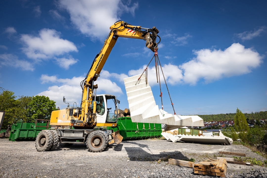 Bagger hebt Betontreppe auf einer Baustelle